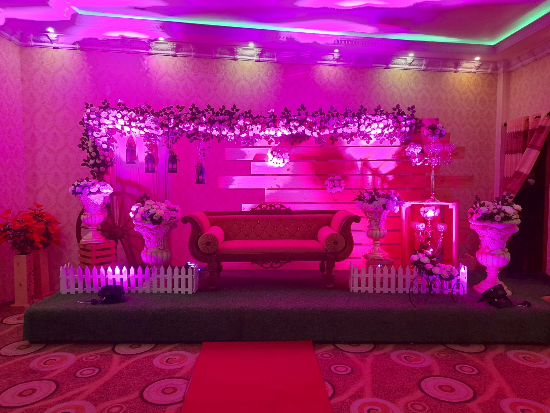 A wedding settee stage with flowers, lanterns and pink lighting